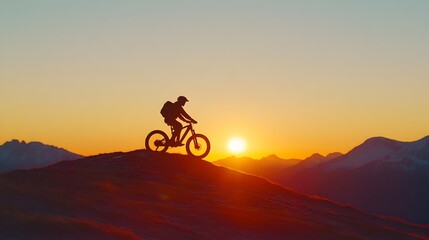 Obraz premium Silhouetted Cyclist Riding into the Sunset over Mountainous Landscape