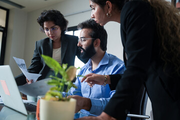 Closeup of Young indian businessman with his employees working together on company project while...