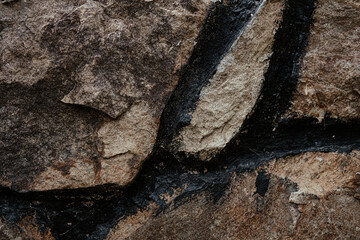 Detailed close-up view of natural rock formation with dark mineral streaks illustrating geological processes in a rugged landscape