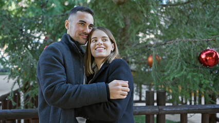 Fototapeta premium A smiling couple embraces in an outdoor setting with festive decorations, conveying love and togetherness.