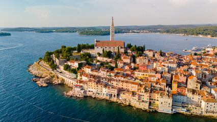 Evening sun casts a golden glow over the charming coastal town of Rovinj, revealing its vibrant buildings, serene waterfront, and the iconic church towering above the picturesque landscape. © Fokke Baarssen