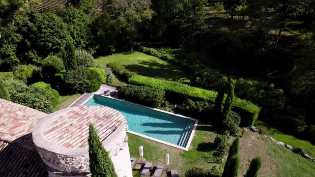 Aerial view of an old building with an outdoor swimming pool nestled in a beautifully decorated yard at Maison Goult, France. The scene captures a blend of rustic charm and modern outdoor elegance.