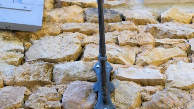 A lamp with a yellow bubble fixture is mounted on an old stone wall, marked with the year 1907 in Maison Goult, France. The scene blends vintage craftsmanship with a rustic aesthetic, historical charm