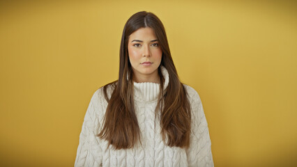 Young hispanic adult woman with a beautiful hairstyle posing confidently against an isolated yellow background.