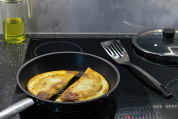 Close-up of fried homemade chebureks on a skillet. Fried dough with meat. Crispy crust