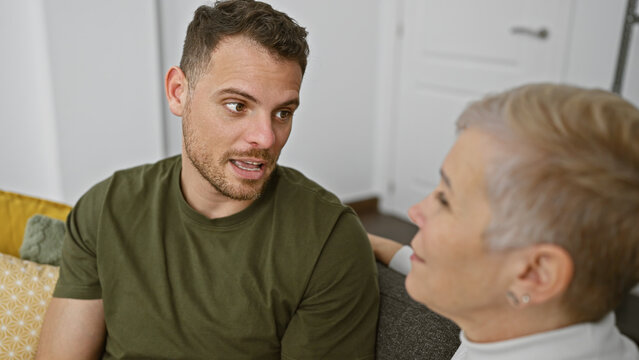 Mature woman and adult man conversing intimately in a cozy living room, depicting family bonding.