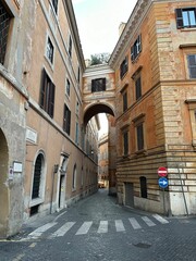 Cobblestone street in Rome, Italy, flanked by historic buildings with a connecting archway above