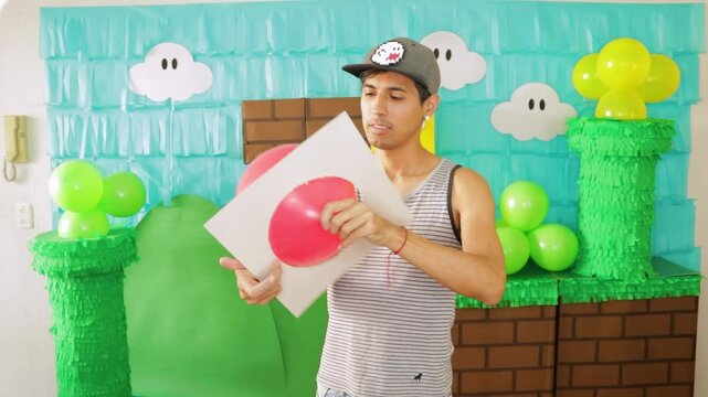 Person sets up colorful video game-inspired decorations with balloons and handmade props