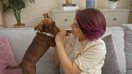 Young woman playing with her dog in a cozy living room.