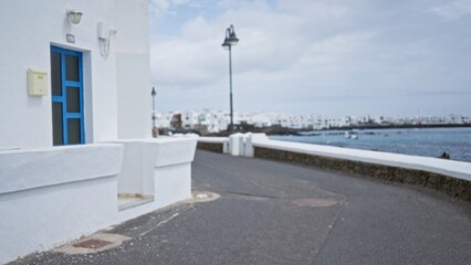 Defocused view of a coastal street with white houses in lanzarote, spain with blue doors and...