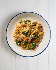 Rice paella with pork loin, mushrooms and broccoli. Top view table.