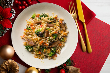 Rice paella with pork loin, mushrooms and broccoli. Top view table with christmas decoration.