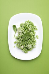 Delicious spinach risotto with parmesan cheese on light green background, top view