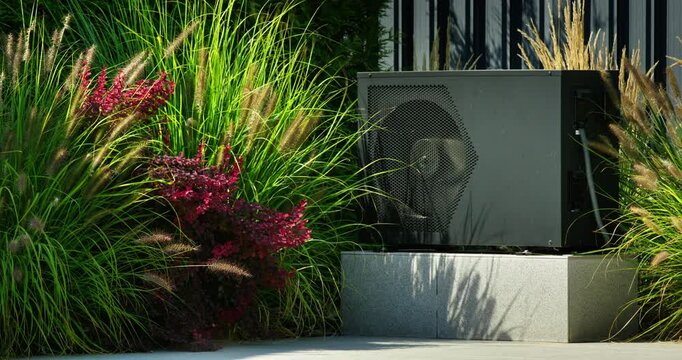 Modern heat pump unit installed by a backyard pool, surrounded by vibrant greenery and blooming plants.