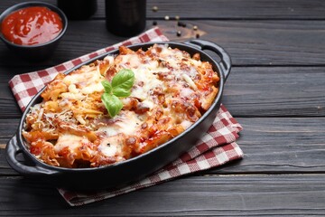 Delicious al forno pasta in baking dish on wooden table