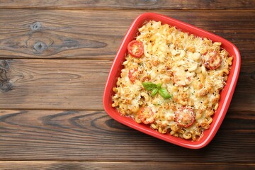 Delicious al forno pasta in baking dish on wooden table, top view. Space for text