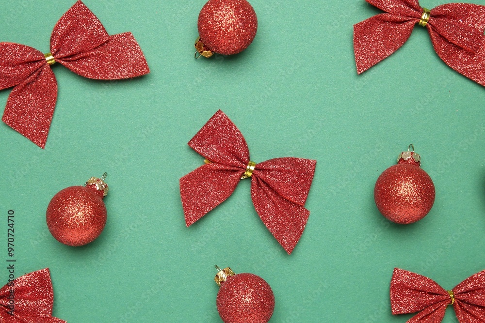 Wall mural Christmas decor. Shiny baubles and bows on green background, flat lay