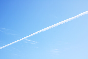 A jet trail can be seen clearly in the bright blue sky above