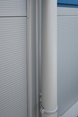 View of a white gutter leaning against white aluminum building siding