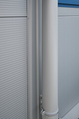 View of a white gutter leaning against white aluminum building siding