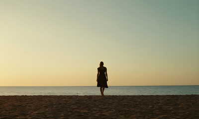 Woman standing on beach at sunset enjoying the view of the ocean