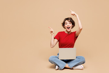 Full body young happy IT woman she wear red t-shirt casual clothes sits hold use work on laptop pc...