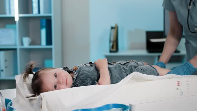 medical examination, portrait of cute little girl at pediatrician's appointment in medical office, female child lying on pelvic table during doctors examination