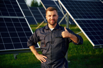 Portrait, standing with arms crossed. Man is working with solar panels outdoors at daytime