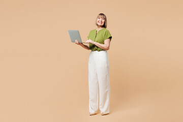 Full body elderly blonde IT woman 50s years old she wearing green shirt casual clothes hold use...