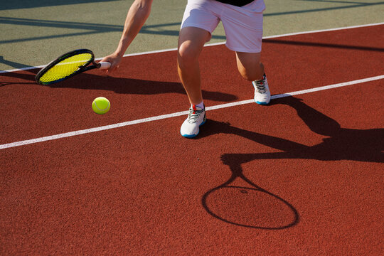 Male tennis player hits difficult ball close-up on tennis court background, tennis game concept