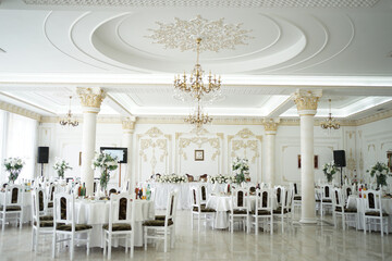 A large festive hall in the restaurant with tables and chairs.