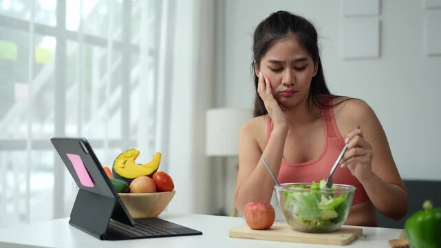 Young Asian woman in good health who is feeling anorexic. Doesn't want to eat. Woman is fasting in a salad bowl. Don't like or get bored with eating fresh, nutritious, tasty, healthy vegetables.