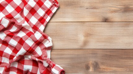 Checkered red and white tablecloth spread on a rustic wooden table. Ideal for country kitchen or picnic concepts.