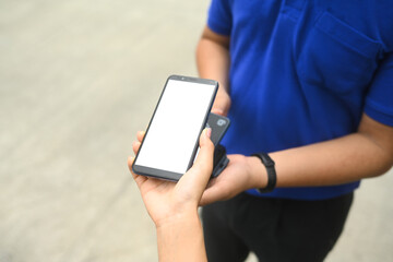 Woman making contactless payment with phone and receiving parcel box from delivery man