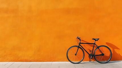 Naklejka premium A modern bicycle parked against a bright orange wall, emphasizing urban living and modern design.