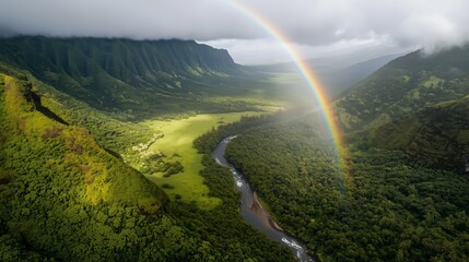 This image showcases a stunning aerial view of a vibrant rainbow arching over a lush, green valley. A winding river meanders through the dense forested landscape.