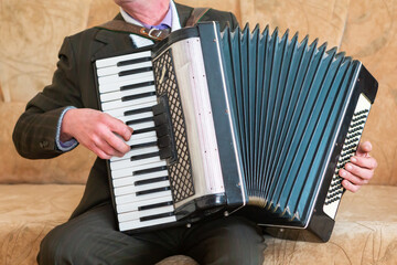 Elderly Man Playing Accordion While Sitting on a Couch in Cozy Living Room.