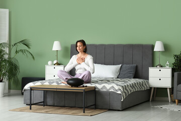 Young woman meditating while sitting on bed