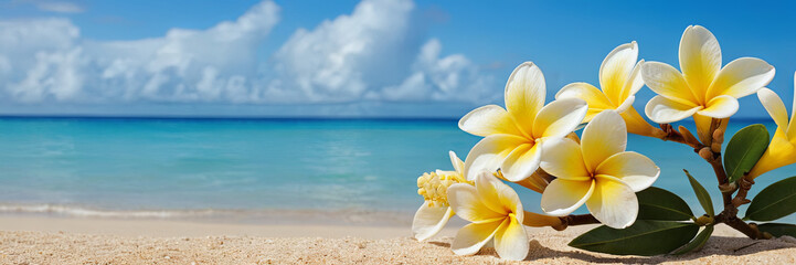 Obraz premium A cluster of vibrant yellow plumeria flowers rests on sandy shores, highlighting the beautiful blue ocean and fluffy clouds under a clear sunny sky