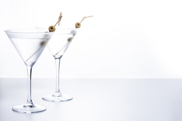 Vodka martini cocktail with vodka and vermouth and green olives on white background. Copy space