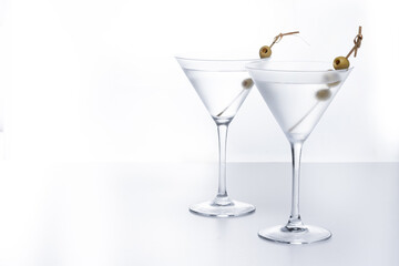 Vodka martini cocktail with vodka and vermouth and green olives on white background. Copy space