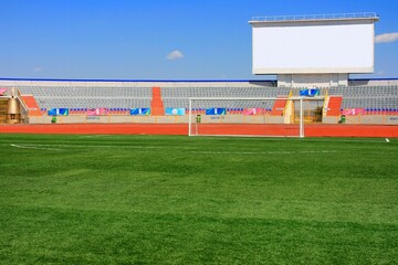 STADIUM - Football field with goal and tablo on blue sky