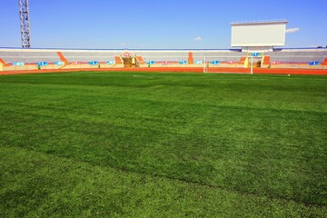 STADIUM - Football field with goal and tablo on blue sky