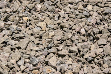 A close-up shot of a pile of gray and brown gravel stones, showing their texture and natural variation