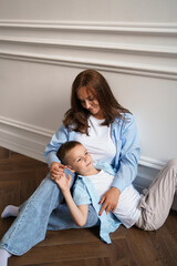 Mom and her son hug each other. Happy mother playing with her adorable baby at home. Loving family. Mother's Day. Vertical image.