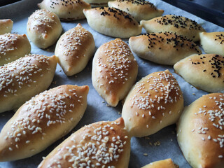 Delicious traditional oriental baked pies with filling, sprinkled with sesame seeds and black cumin