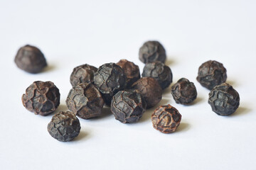 Close up photograph of dry black peppercorns. Food spices for cooking. Macro, details and texture, realistic. Isolated on white background. 