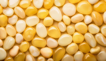 Fototapeta premium Wet pebbles in shades of yellow, forming seamless glossy surface. Top view.