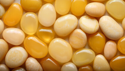 Fototapeta premium Wet pebbles in shades of yellow, forming seamless glossy surface. Top view.