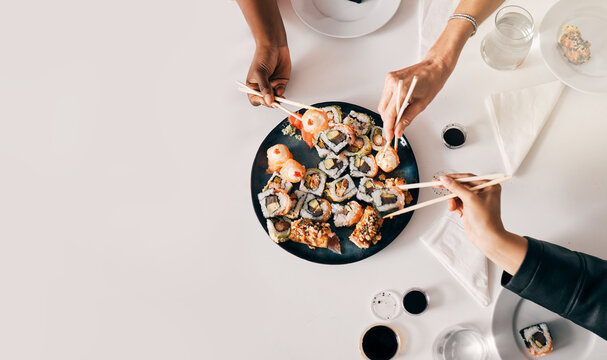 Above, sushi or hands of people with chopsticks for lunch, luxury meal or takeaway food in office. Japanese cuisine, utensils or women at table for sharing, high quality catering or business expense